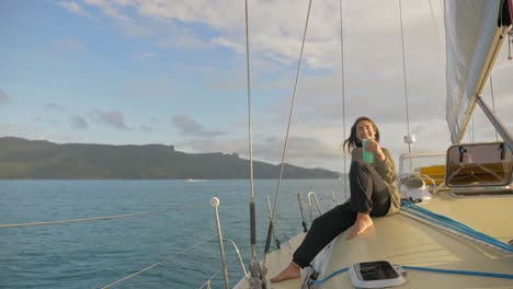 beautiful woman sitting on a boat, offering a cup of drink while sailing across hook passage in whitsunday islands, qld