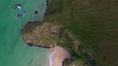 Tilting-drone-shot-from-the-headland-to-the-cliffs-and-sand-at-Traigh-Mhor-beach-in-Tolsta-village-on-the-Outer-Hebrides-of-Scotland