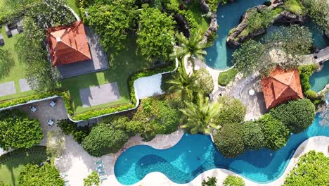 aerial - birdseye shot of beautiful resort with pools and waterslides surrounded by lush jungle