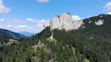 panorama of the lonely rock rising above evergreen forest at piatra singuratica in hasmasul mare, romania