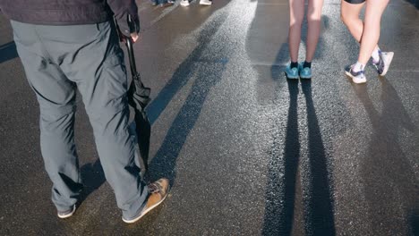 people standing on a wet street with their shadows cast on the ground