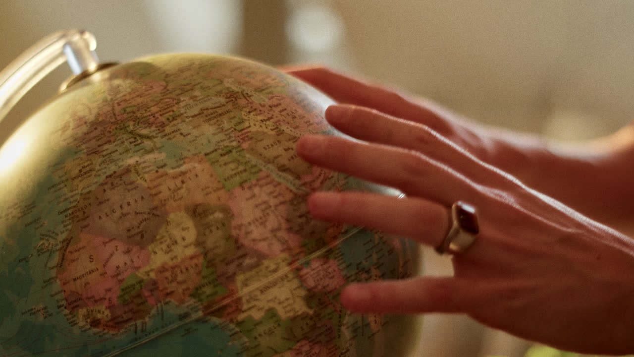 A hand gently touching a globe, showing world geography.