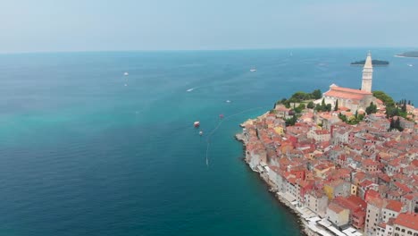 Fliegen-Durch-Eine-Stadt-Mit-Einer-Kirche-Im-Zentrum-Und-Dem-Meer-Drumherum