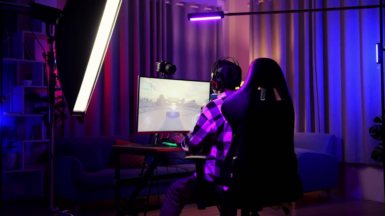 Back View Of Asian Boy Streamer Screaming Goal Celebrating Winning Car Racing Game Over Network On Personal Computer.  Live Stream Video Game, Desk Illuminated By Rgb Led Strip Light