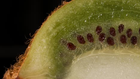 macro shot slice of fresh green kiwi and seeds fruit on black background. juicy fresh ripe delicious sliced kiwi fruit, close-up.