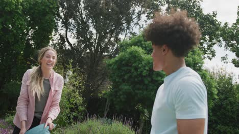 Happy-diverse-couple-playing-in-garden-on-sunny-day