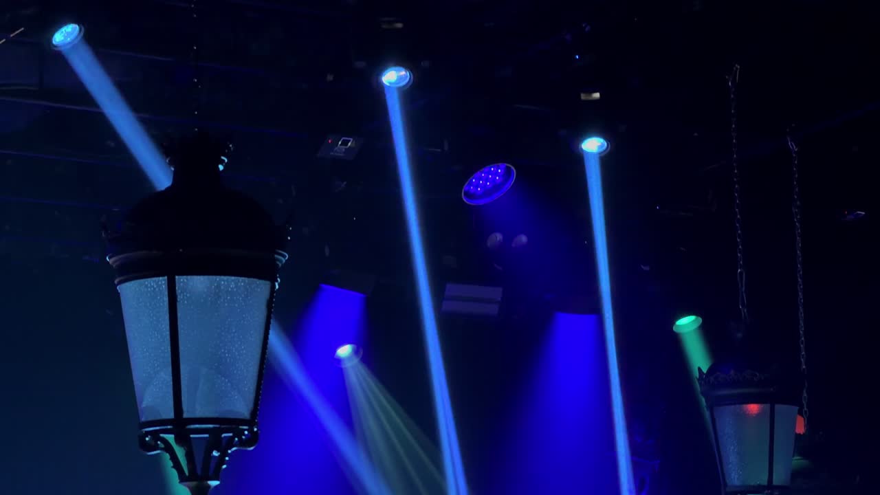 Dynamic 4K footage of colorful stage lights and laser beams moving through a dark nightclub interior, capturing a high-energy entertainment and party atmosphere