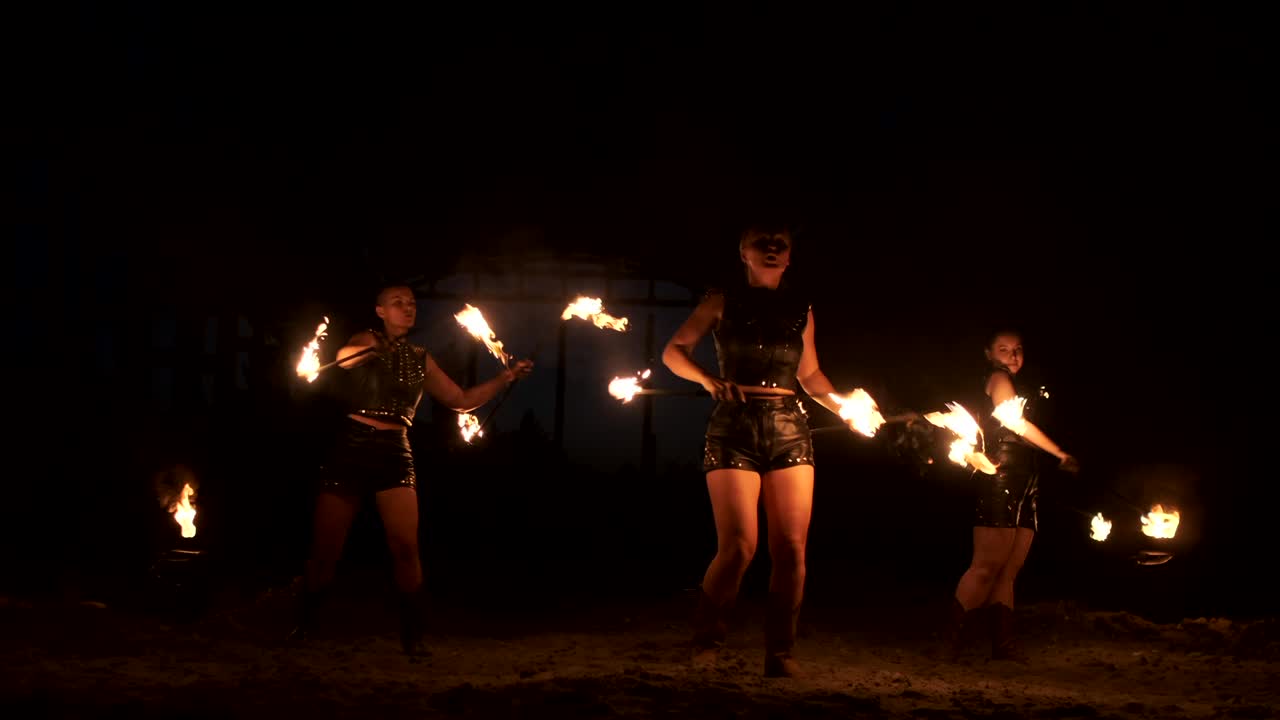 espectáculo de fuego profesional en el antiguo hangar de la aeronave muestran artistas de circo profesionales tres mujeres en trajes de cuero y un hombre con dos lanzallamas.