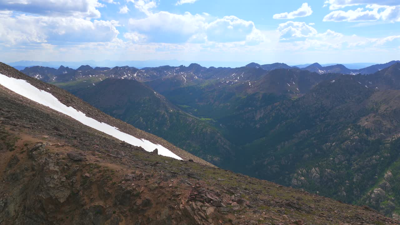 Hiker hiking cairn to top of 14er summit Mount of the Holy Cross peak Sawatch Range Colorado aerial drone Rocky Mountains spring summer snow field cornice chute blue sky Elk Mountains view forward