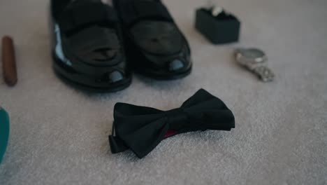 black bow tie shoes watch and ring box arranged for wedding groom preparation scene