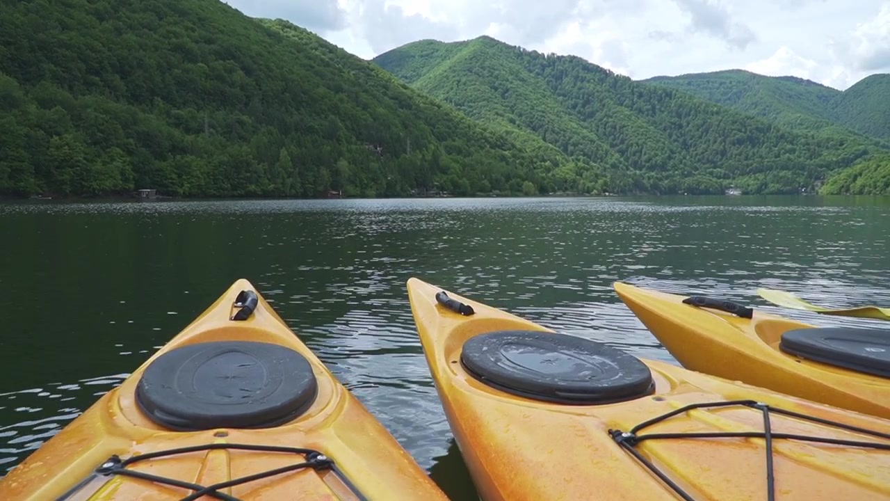 Kayak gialli galleggiano su un tranquillo lago di montagna circondato da rigogliose colline verdi, perfetto per contenuti di avventura all'aperto