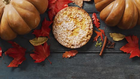 Video-of-autumn-leaves,-pumpkin,-spices-and-pie-on-wooden-background
