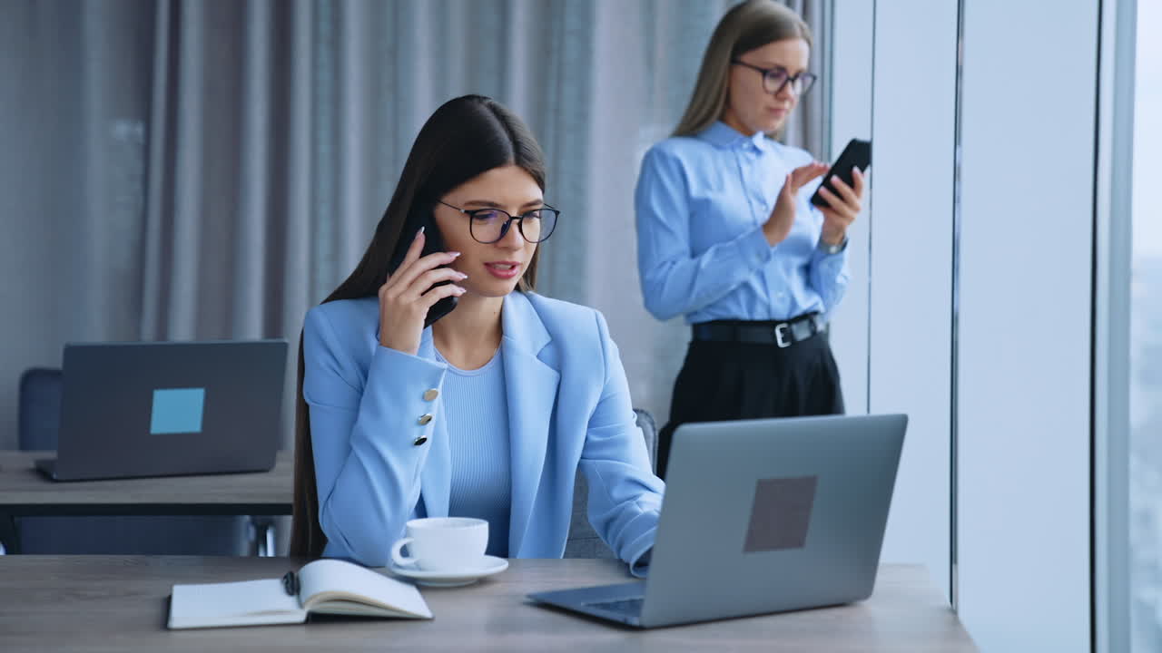 Modern office employees at work. Female workers using modern gadgets. Ladies speaking on the smartphone.