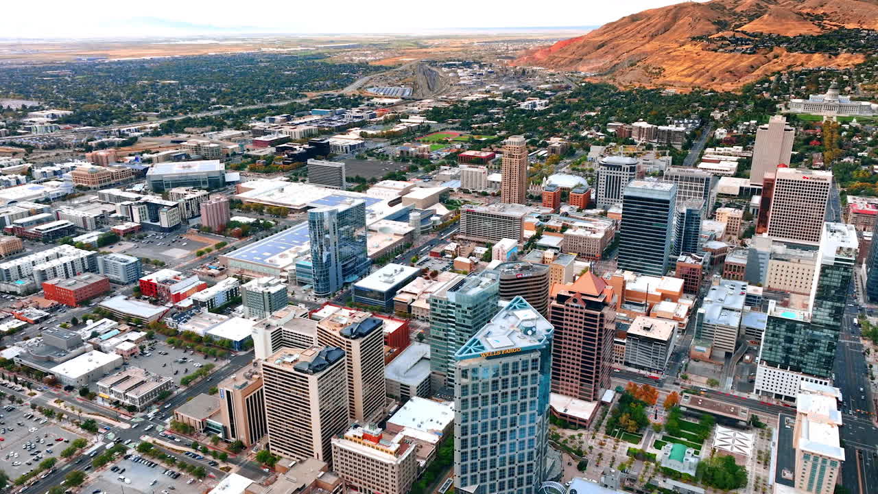 Salt Lake City, USA, 14 August 2025: Flight above the urban landscape of modern Salt Lake City, Utah, USA. Moving above the high-rise buildings approaching the low-rise green residential area at the mountain foot