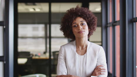 Millennial-black-businesswoman-smiling-to-camera-by-the-window-in-an-office,-close-up