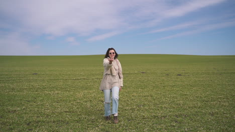 a young beautiful brunette girl walks through a green meadow