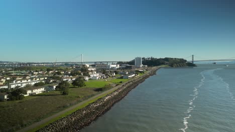 pan drone shot of treasure island and san francisco-oakland bay bridge with pacific ocean in california, usa