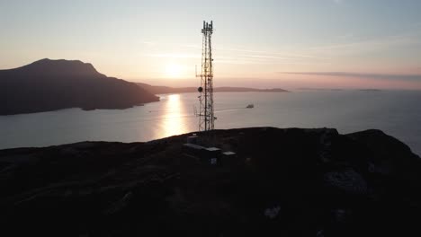 puesta de sol sobre el mar con una torre de radio y un barco en escocia