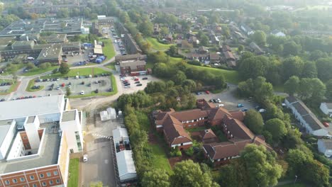 Aerial-view-looking-down-over-British-hospital-car-park---medical-buildings