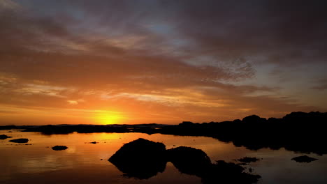 Puesta-De-Sol-Dorada-Con-Cielo-En-Llamas,-Reflejos-En-La-Superficie-Del-Agua,-Tonos-Cálidos