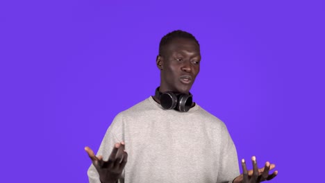 attractive joyful young african man looking to the camera in headphones on neck smile happy talks at camera, explaining something. positive emotions. male portrait. contemporary human