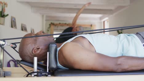 Focused-diverse-seniors-stretching-in-pilates-class-with-female-coach,-unaltered,-in-slow-motion