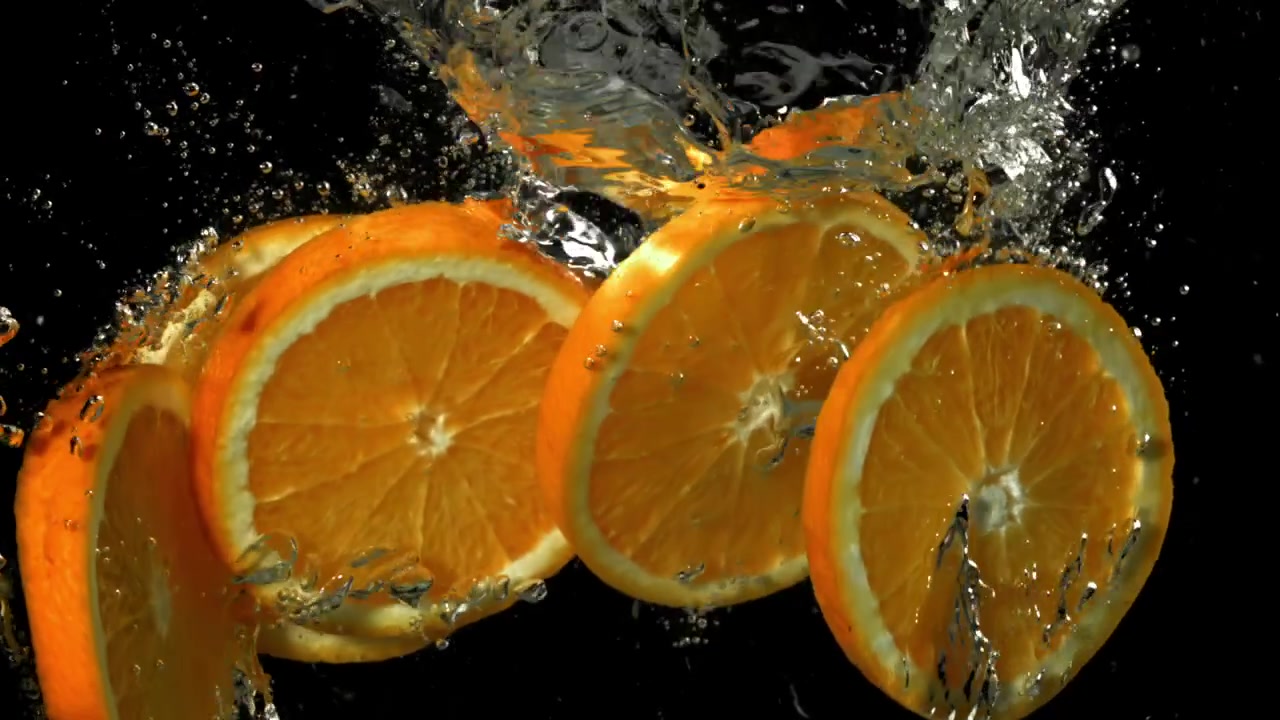 Slow motion di fette d'arancia fresche che schizzano nell'acqua