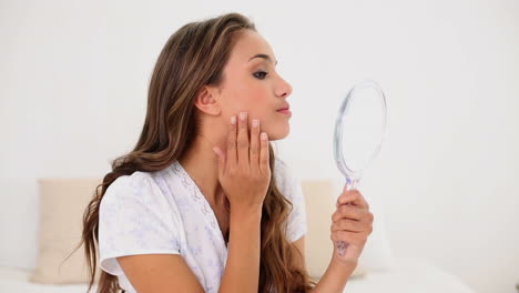 young woman admiring herself in hand mirror