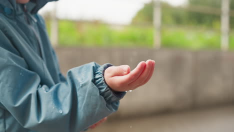 niño atrapando gotas de lluvia en su mano