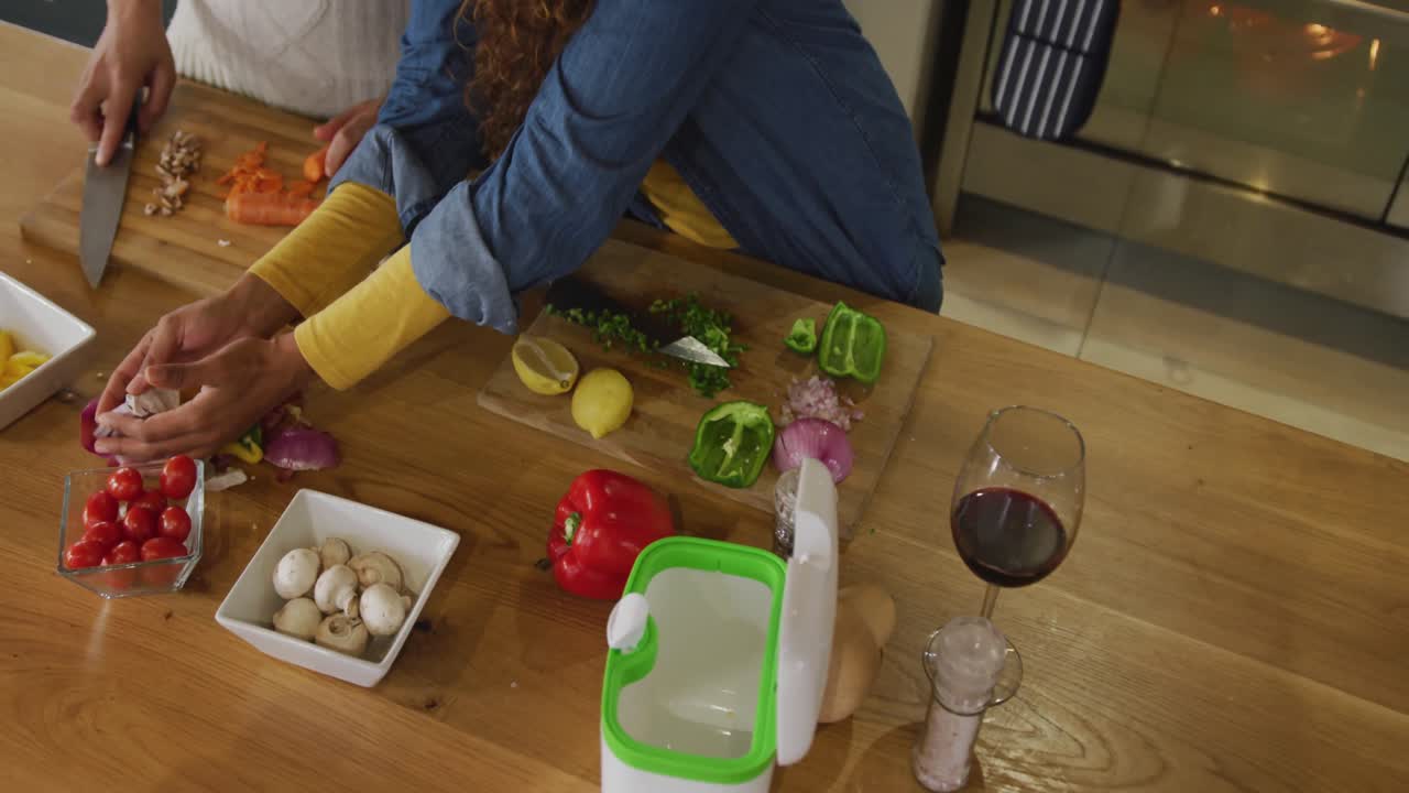 Video of happy biracial couple preparing meal together and drink wine