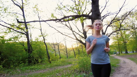 Hermosa-Mujer-En-Camiseta-Hace-Una-Carrera-En-El-Tiro-De-Steadicam-De-Bosque-De-Primavera