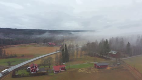 aerial shot of a farm in sweden covered in clouds