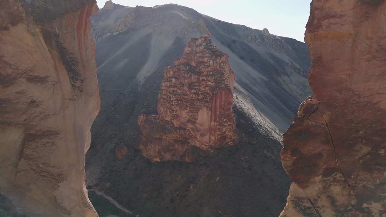 Drone slow epic fly through rock formation at Leslie Gulch Oregon to reveal rock spire on hillside in morning back light