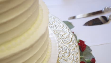 Primer-Plano-De-Pastel-De-Bodas-De-Vainilla-Con-Cuchillos-En-El-Fondo