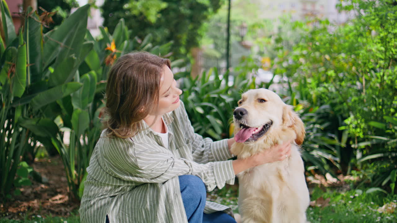 Joyful woman petting dog in green park closeup. Happy golden retriever enjoying