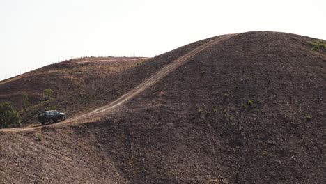 Off-road-SUV-parked-on-a-barren-hilltop-in-Algarve,-Portugal