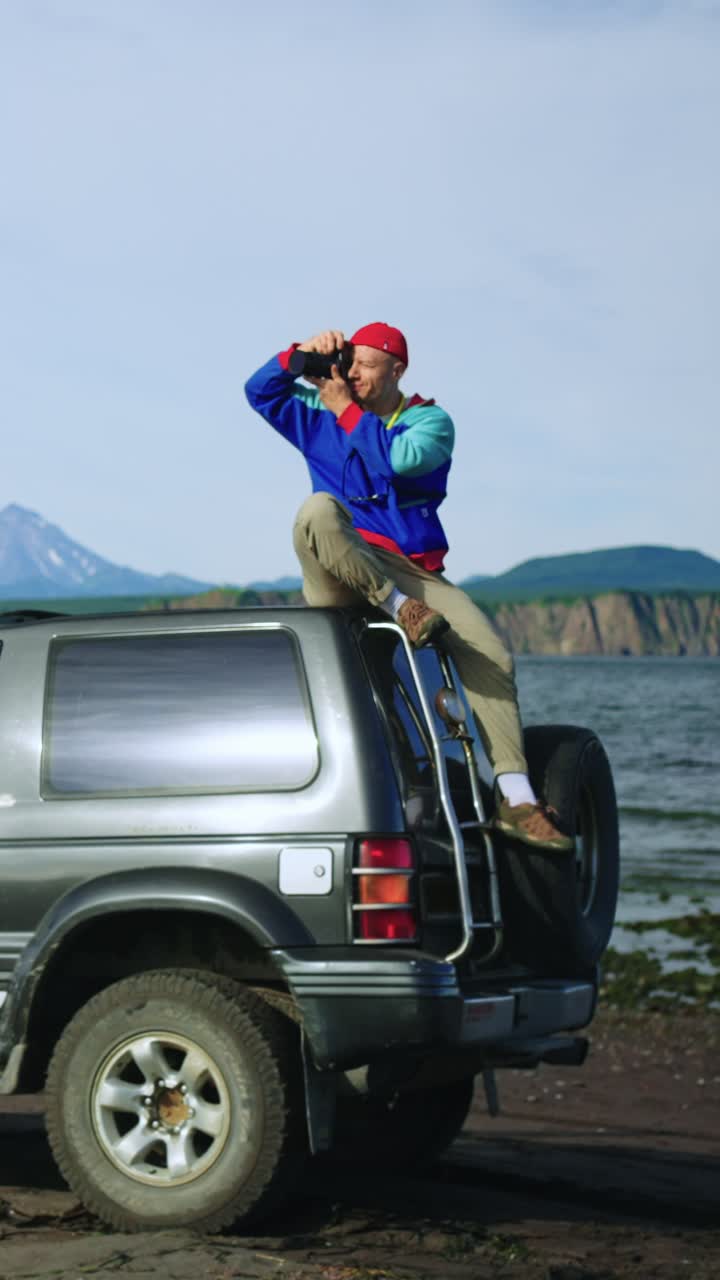 Fotografo seduto su un SUV che scatta foto di un paesaggio panoramico