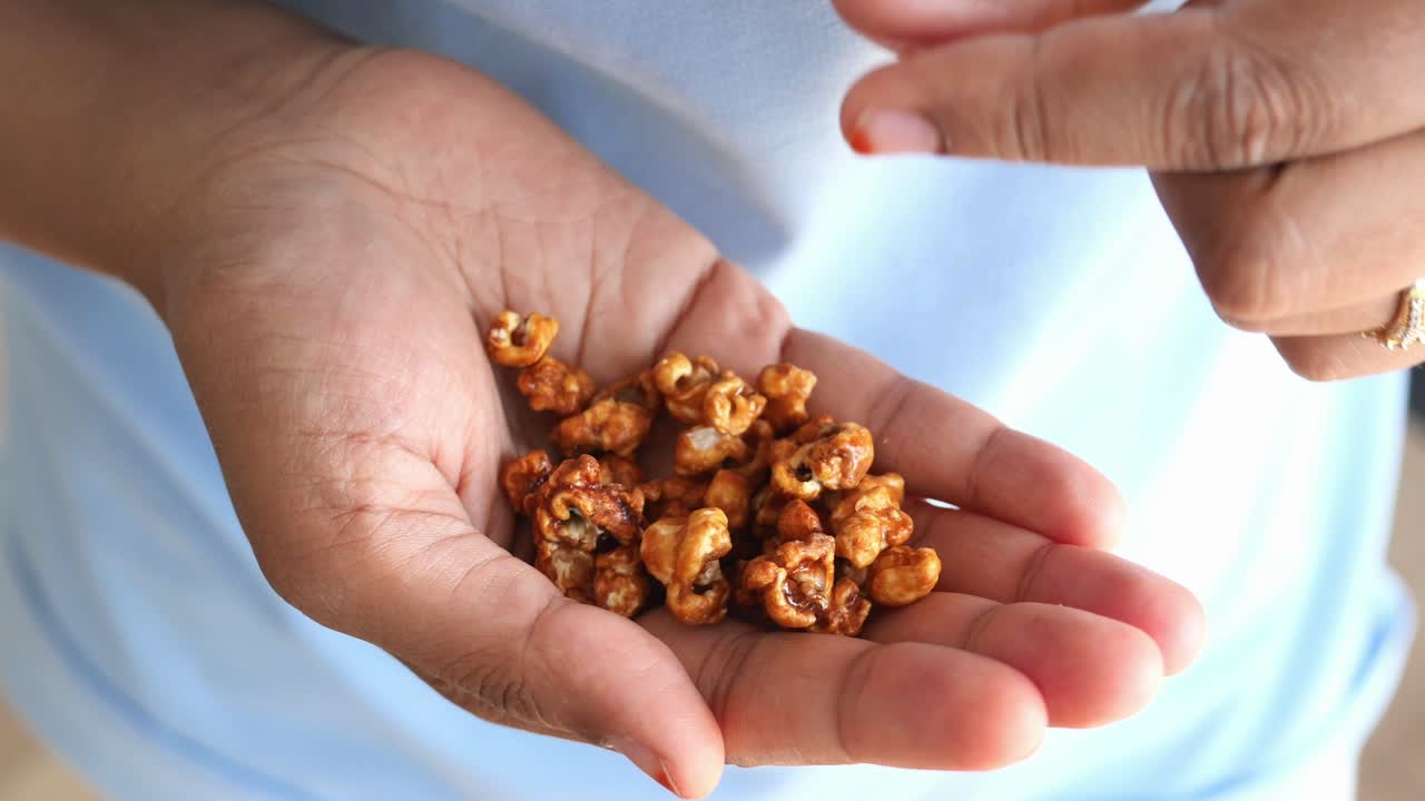 카라멜 팝콘 한 손을 들고 있는 손의 가까운 모습