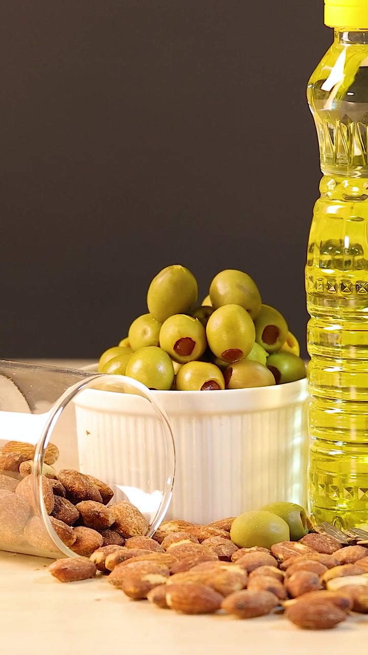 Una disposizione verticale di alimenti chetogenici tra cui avocado, pancetta, burro e vari oli da cucina.