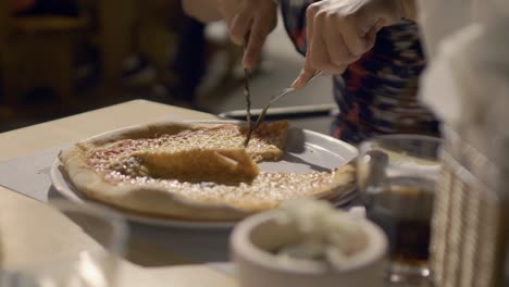 Static-shot-of-woman's-hands-cutting-a-pizza