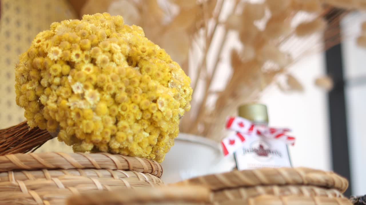 A close up of a bouquet of dried yellow flowers in a wicker basket