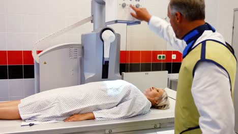 el médico establece la máquina para radiografiar a una paciente femenina
