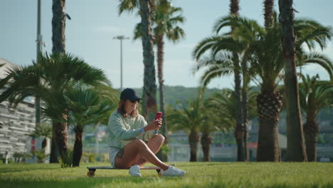 woman using phone on skateboard in a park