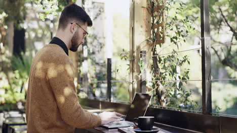 a young man using his laptop at a cafe