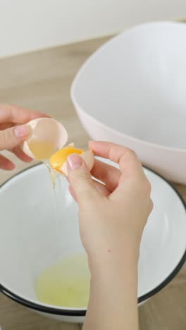 vertical clip of cracking egg and separating yolk and white into separate bowls