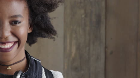 retrato de una hermosa joven mujer afroamericana sonriendo feliz disfrutando del éxito mujer negra con un peinado afro funky en fondo de madera mitad de la cara