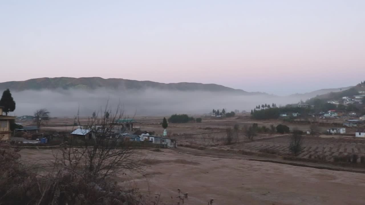 pequeño pueblo remoto en las faldas de las montañas con niebla y cielo plano por la mañana desde un ángulo plano