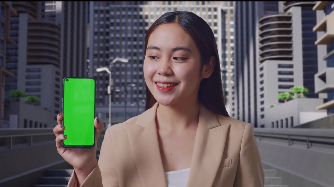 도시 거리에서 서 있는 동안 녹색 화면 휴대전화를 보여주는 미소를 가진 아시아 사업가의 근접