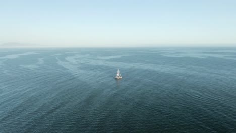 Aerial-of-tourist-sailboat-on-the-Pacific-ocean-during-sunset,-near-the-coast-of-Santa-Barbara,-California