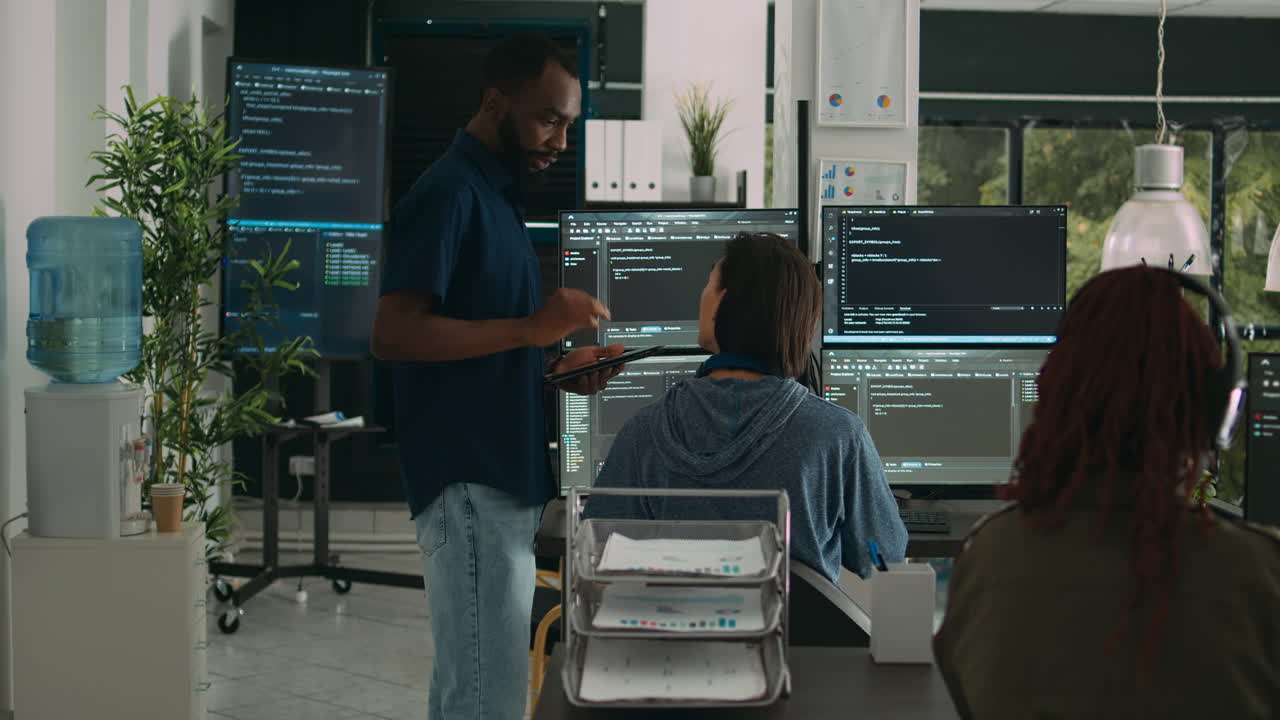 Software programmers talking about algorithms on big screen and tablet